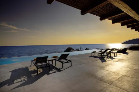  Sunbeds and pool framed by sunset horizon