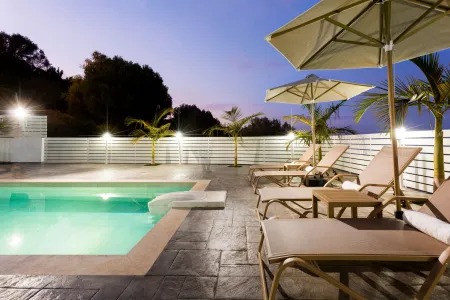  Fenced pool area with sunbeds, umbrellas and ambient lighting